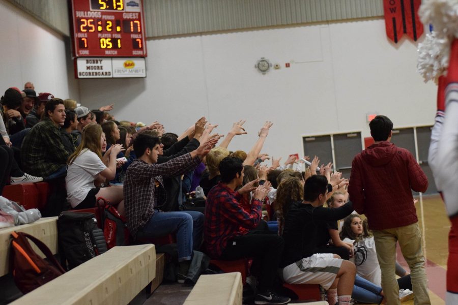 Students silently cheer while a player takes a foul shot.

