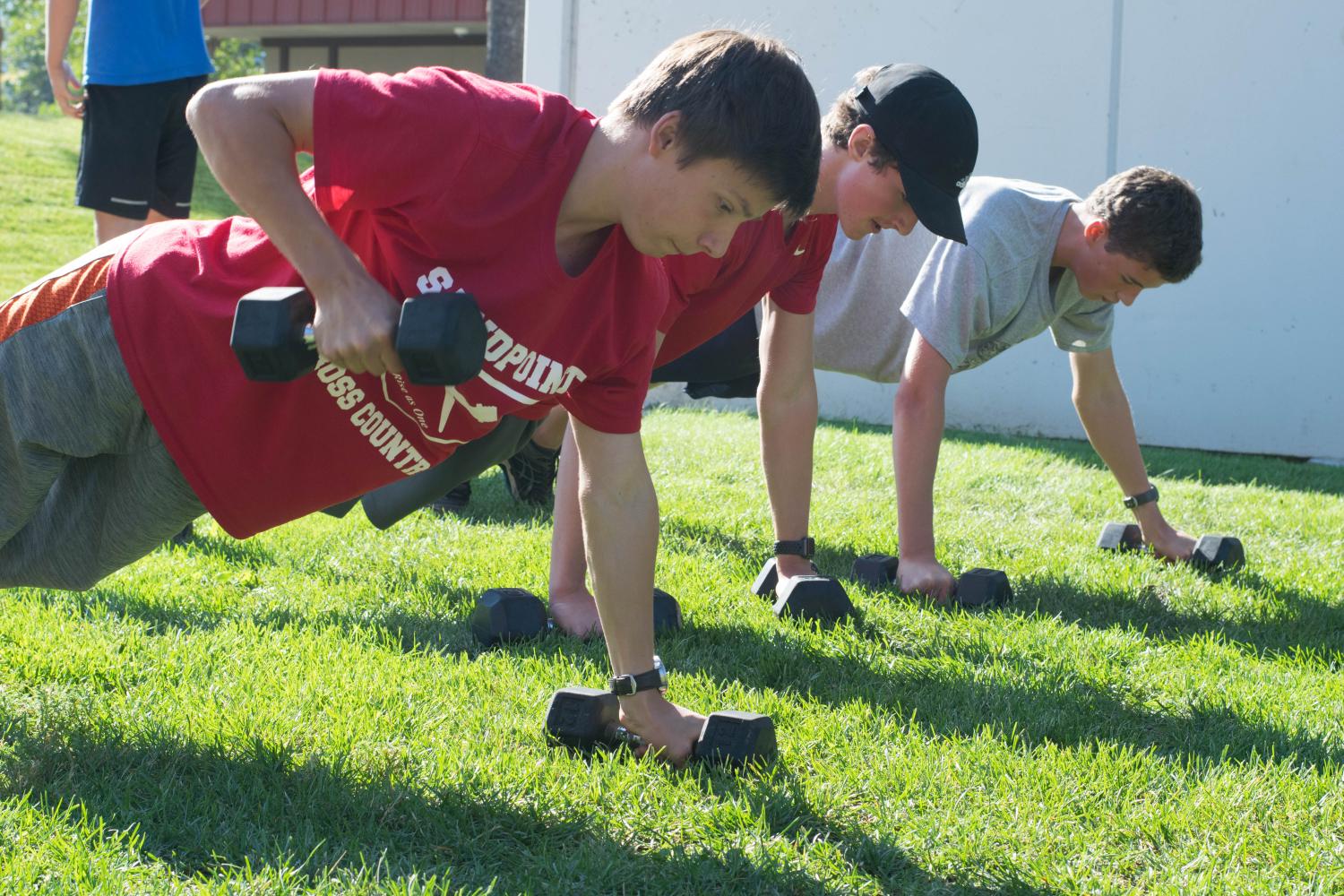 Freshman Nickolai Braedt, Junior Ben Robinson, and Freshman Henry Fite doing barbell push up walks. 