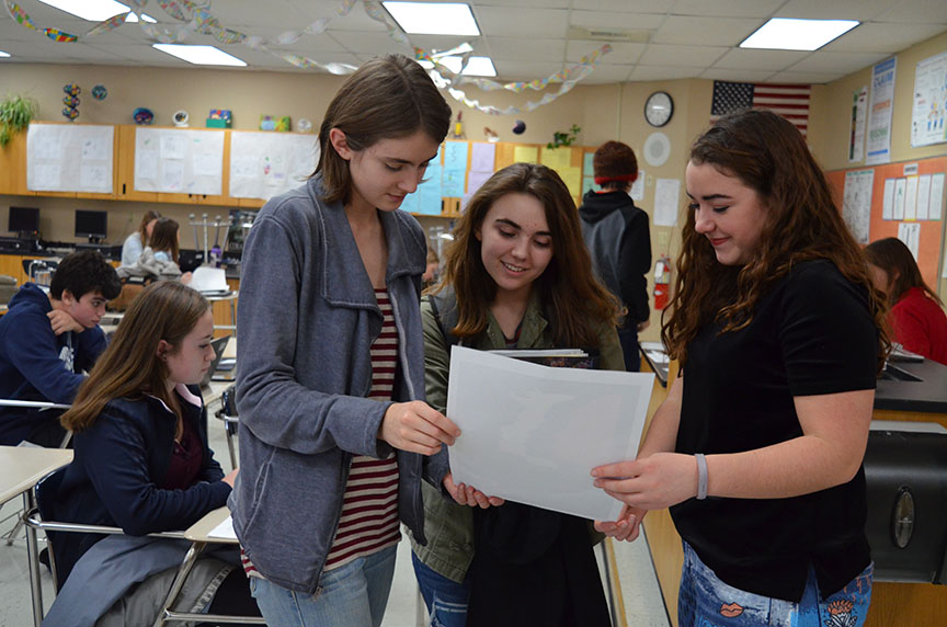 Left to right, Human Rights Club President Soncirey Mitchell, President-Elect Emma Dreier, and Vice-President Emma Reed study a poster advertising the Womens March.