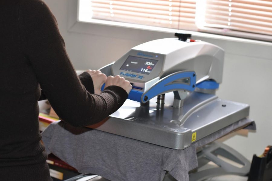 CTE teacher, Nayla Morton, goes through the printing process using a hot press to create a T-shirt.