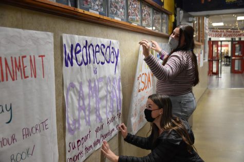 Members of student council hang handmade posters that say what each dress up day during spirit week is.